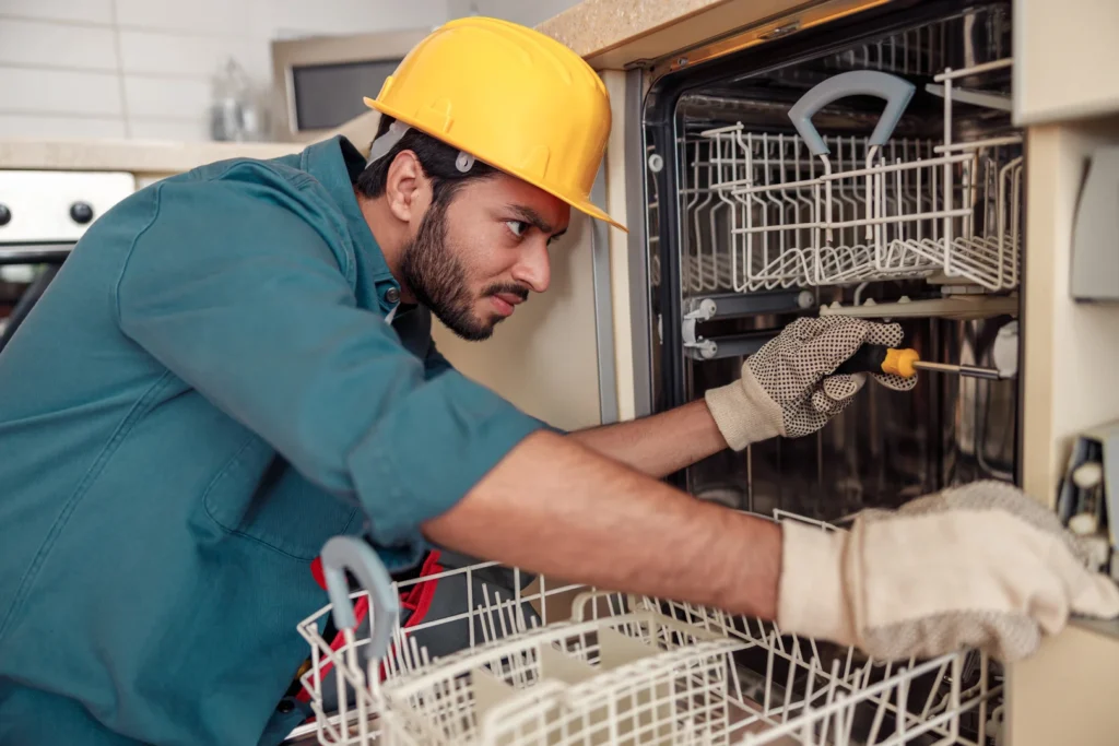 A plumber inspections a dishwasher for repair