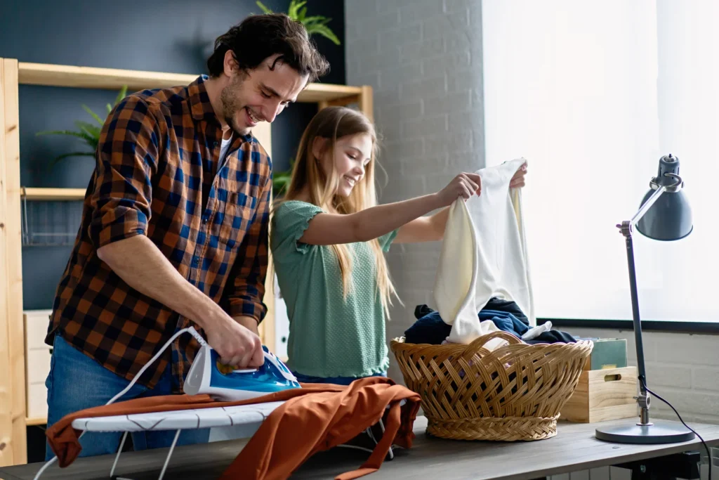 A father folding Laundry and ironing with his kid