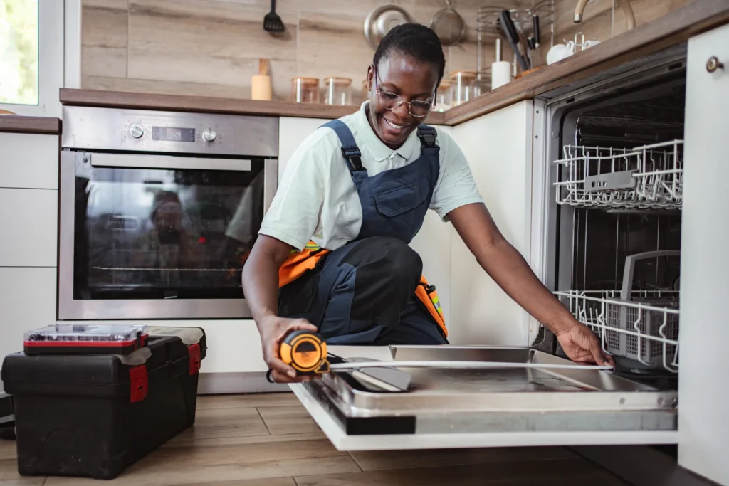 A plumber measuring a dishwasher for installation